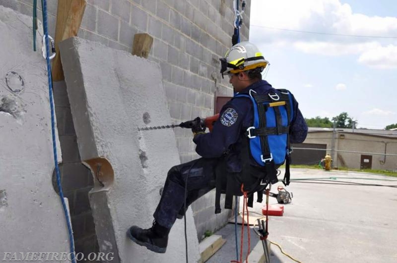 FF/Technician Daniel (DJ) Matthews drills holes in reinforced concrete while suspended on rope at FEMA USAR SCT Course.